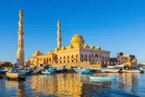 Mosque with fishing boats at sea in egyptian landscape. In the city Hurghada in Egypt I took this landscape photo with this new gold colored building. In front of the building there are many little boats floating on the sea water. The view at this coast is very beautiful.